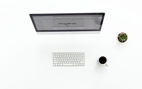 kadr z góry, biurko z monitorem, klawiaturą i kawą
