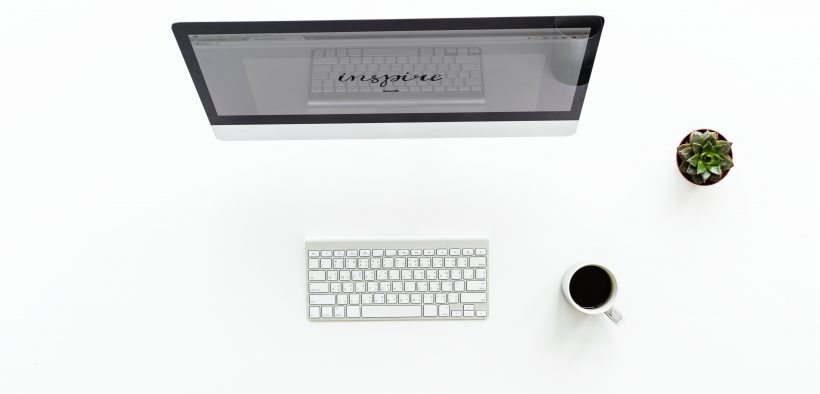 kadr z góry, biurko z monitorem, klawiaturą i kawą