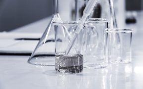 menzurki, szklane naczynia chemiczne stojące na stole