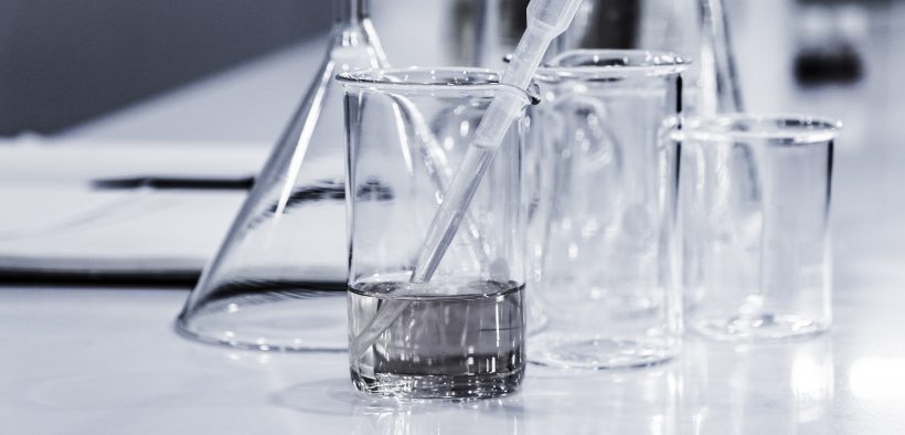 menzurki, szklane naczynia chemiczne stojące na stole