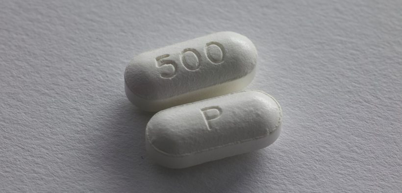 dwie białe tabletki leżące na jasnej powierzchni