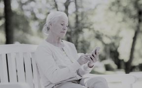 starsza kobieta trzymająca w dłoniach smartfon