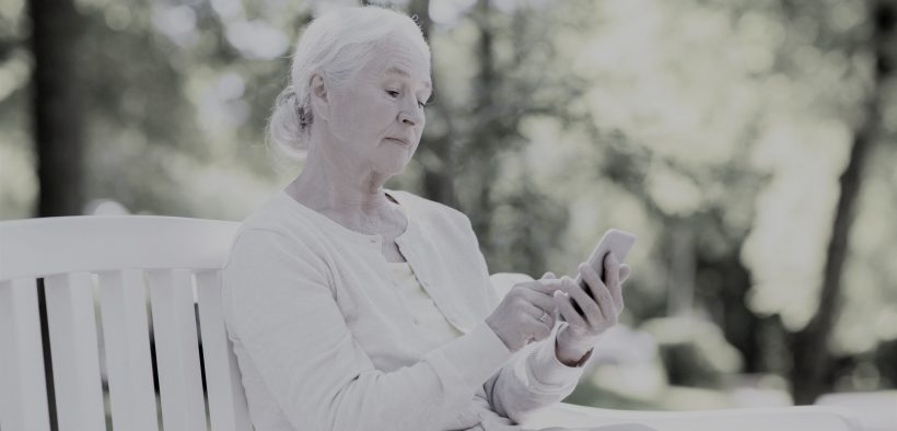 starsza kobieta trzymająca w dłoniach smartfon