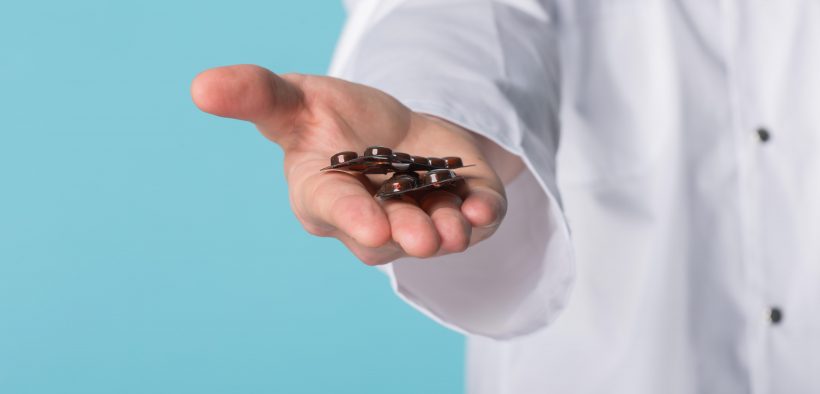 farmaceuta trzymający na dłoni tabletki