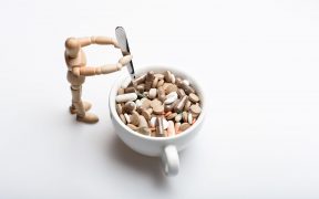 Miniaturowy, Drewniany ludzik mieszający antybiotyki w filiżance