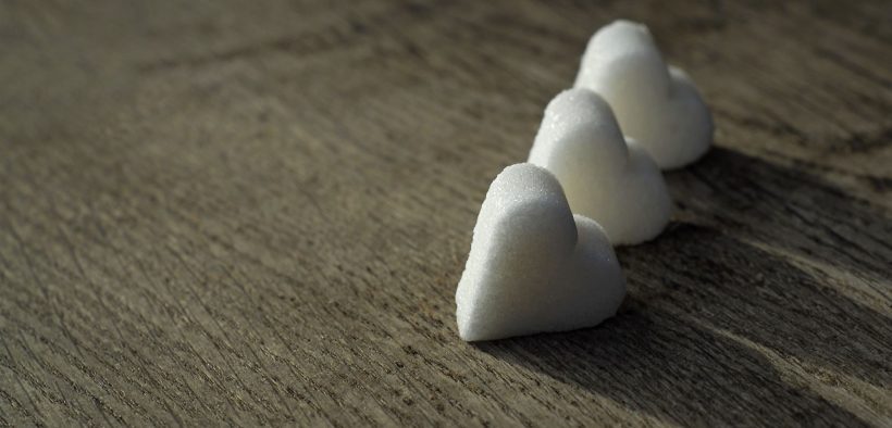 3 "kostki"Cukru w kształcie serca leżące na blacie.