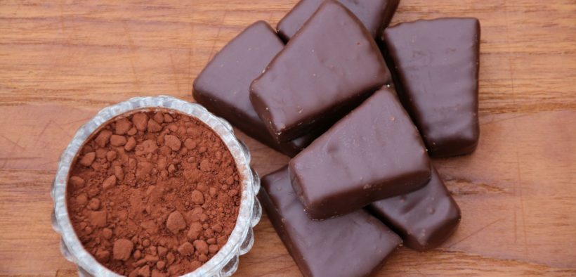kakao w proszku w filiżance i czekoladki leżące na blacie