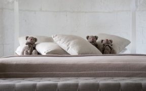 tzy pluszowe misie leżące wśród poduszek na łóżku