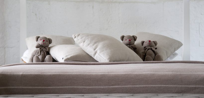 tzy pluszowe misie leżące wśród poduszek na łóżku