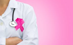 lekarka w kitlu ze stetoskopem na szyi i różową wstążką na piersi